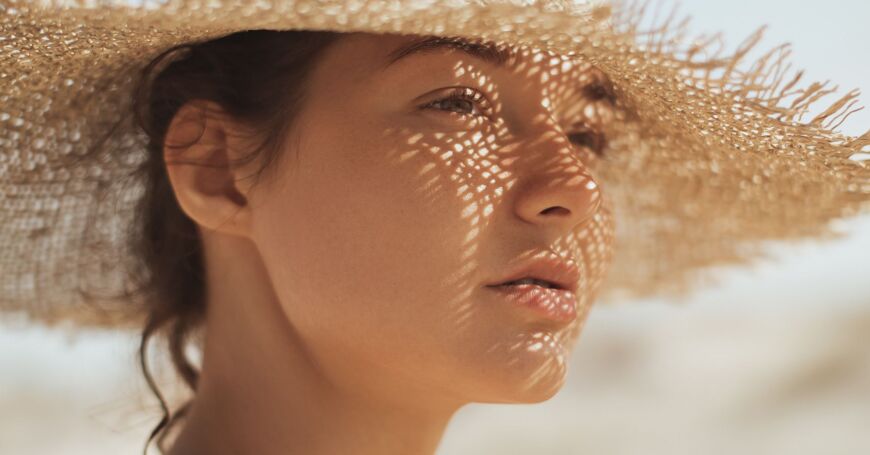 Nainen tietää, että helteellä kannattaa suojautua auringolta päähineellä